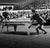 Black and white image of two people playing table tennis.